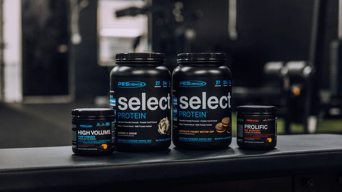 Select Protein and pre-workout tubs lined up on a dark gym counter